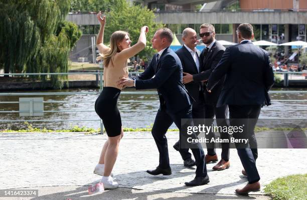 Member of the topless feminist action group Femen throws fake bloody 50 euro notes at German Chancellor Olaf Scholz as she is arrested while...