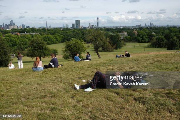 Couple relax lying on the grass cuddling each other on a sunny day in Primrose Hill park on June 29, 2022 in London, United Kingdom. The London...