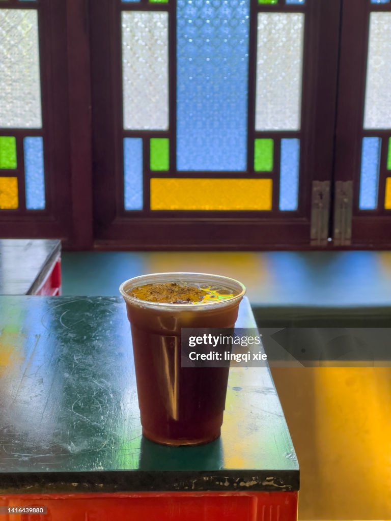 Iced coffee on table behind stained glass