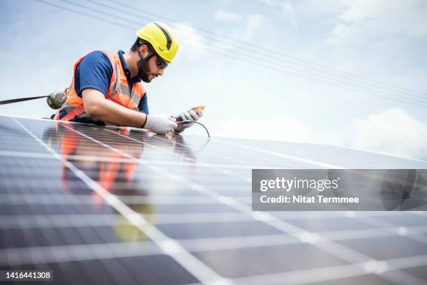 on-site quality control and testing of photovoltaic modules installation. male solar engineer in a safety harness use multi-meter to measure ground resistance test and insulation test of solar panels in a solar power station. - multimeter stock pictures, royalty-free photos & images