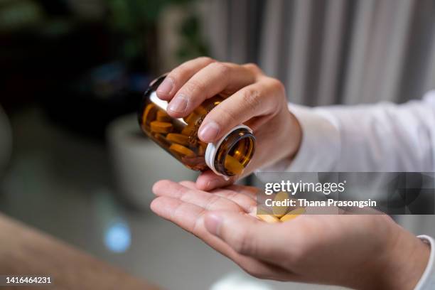 close up of human hands. he is taking pill - anti impotence tablet stock pictures, royalty-free photos & images