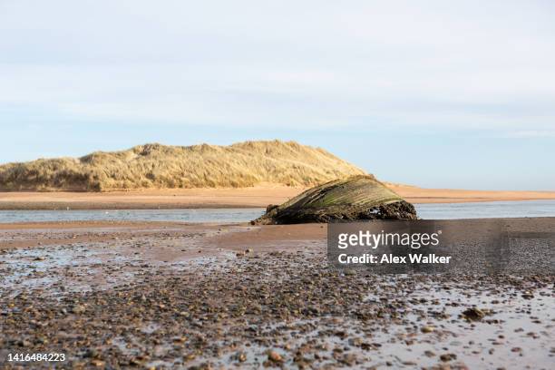 wrecked wooden hull of boat on sandy beach - hull uk stock pictures, royalty-free photos & images