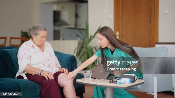 doctora que visita a su paciente anciano en su casa para un chequeo médico - swollen fotografías e imágenes de stock