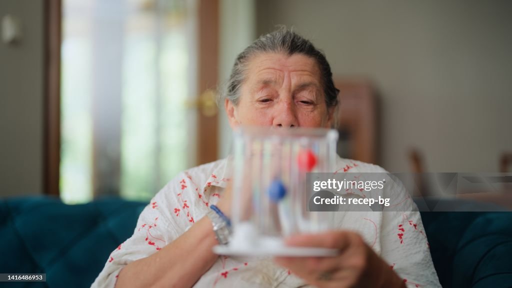 Senior woman using spirometer