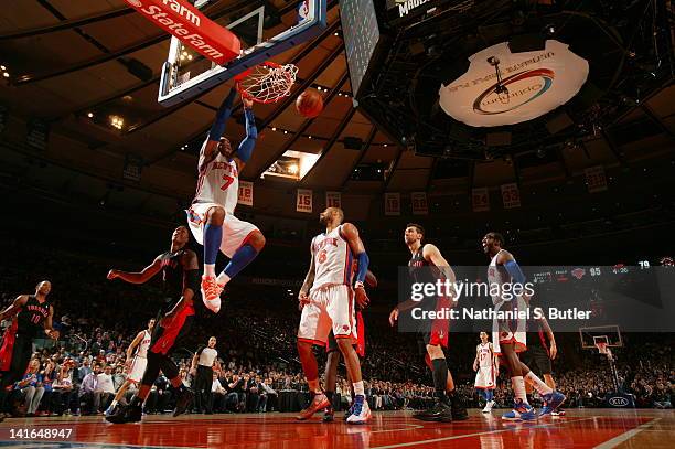 Carmelo Anthony of the New York Knicks hangs from the rim after a dunk during the game against the Toronto Raptors on March 20, 2012 at Madison...