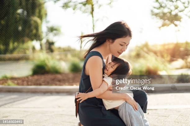 beautiful young asian mother holding her little girl in her arms at the park. - chinese mothers day foto e immagini stock