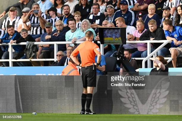 Referee Jarred Gillett checks the VAR screen of the red card given to Kieran Trippier of Newcastle United which is overturned to a yellow card during...