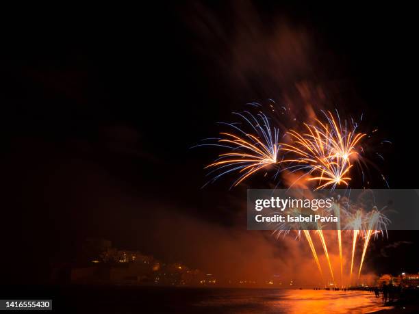 low angle view of firework display over sea at night - praia noite imagens e fotografias de stock