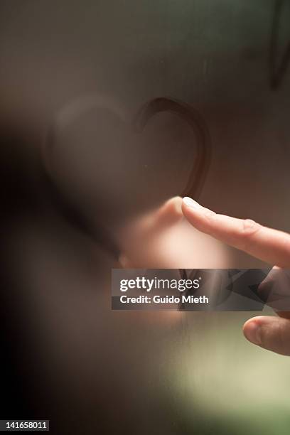 finger writing heart on steamy mirror - mirror steam stockfoto's en -beelden
