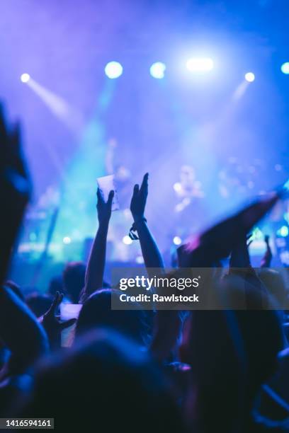 vertical photo of an unrecognizable person clapping hands at a music concert - concert crowd stockfoto's en -beelden