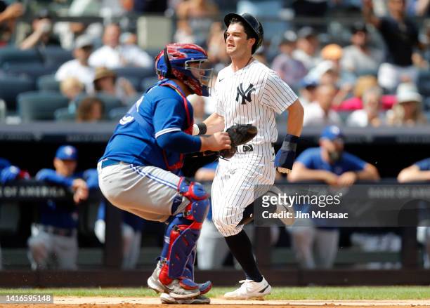 Andrew Benintendi of the New York Yankees scores a run during the third inning past Alejandro Kirk of the Toronto Blue Jays at Yankee Stadium on...