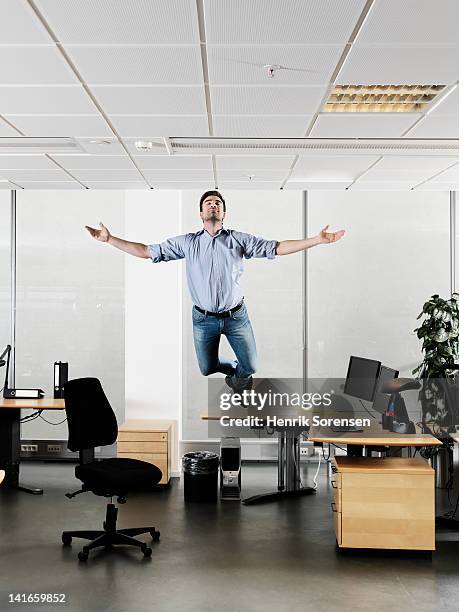 young businessman floating above the desk - levitating stock pictures, royalty-free photos & images