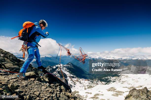 a mountain climber throws a climbing rope from a mountain top before rappelling - alex pix photos et images de collection