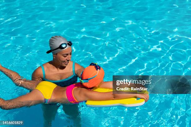 little girl learns to swim with her swimming instructor - kids swim caps stock pictures, royalty-free photos & images
