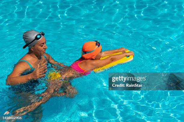 little girl learns to swim with her swimming instructor - aqua star pool stock pictures, royalty-free photos & images