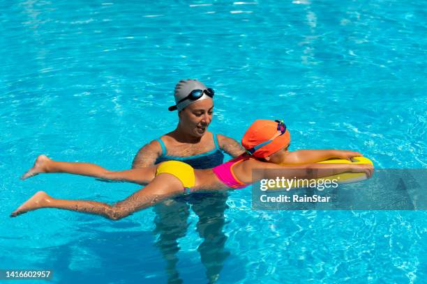 little girl learns to swim with her swimming instructor - aqua star pool stock pictures, royalty-free photos & images