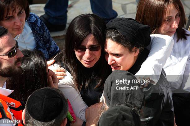 Friends and relatives comfort Eva Sandler , the wife of Jonathan Sandler, and the mother of Gabriel 4, Arieh 5, during their funeral at the Givat...