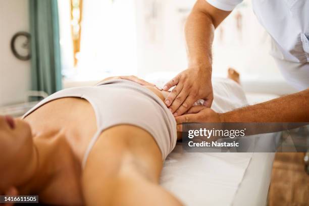professioneller masseur, der am patientenmagen arbeitet - druckpunkt stock-fotos und bilder