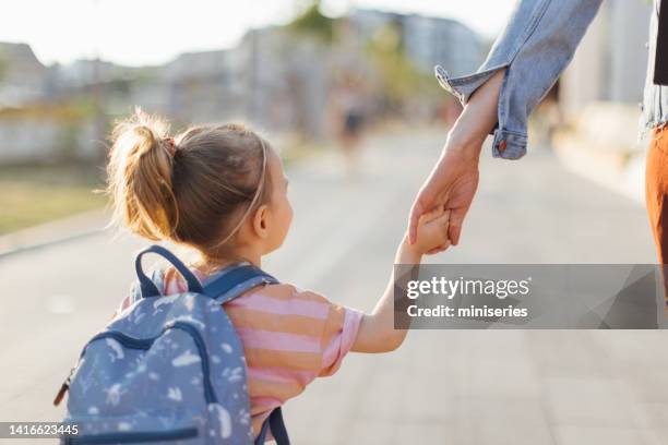 anonymous daughter being taken to school by her mother - school bag stockfoto's en -beelden