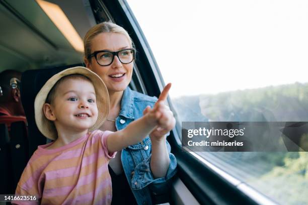 happy mother and daughter having fun while riding on the train together - trein stockfoto's en -beelden