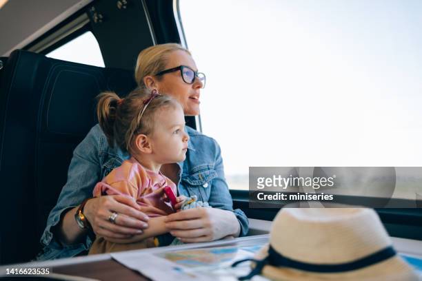 mother and daughter enjoying riding on the train together - looking at subway map stock pictures, royalty-free photos & images