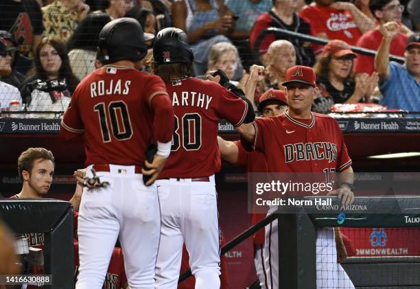 Manager Torey Lovullo of the Arizona Diamondbacks celebrates with Jake McCarthy and Josh Rojas who both scored on a throwing error by Brendan Donovan...