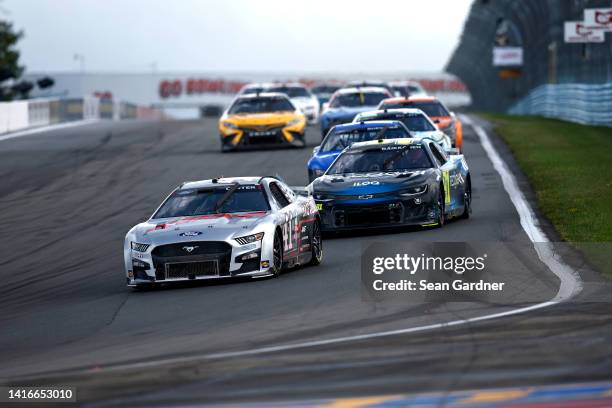 Cole Custer, driver of the HaasTooling.com Ford, and Kimi Raikkonen, driver of the Recogni Chevrolet, race during the NASCAR Cup Series Go Bowling at...