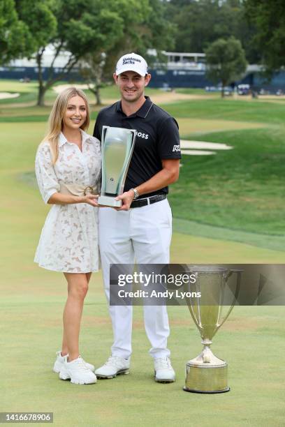 Patrick Cantlay of the United States poses with the BMW Trophy and The Western Golf Association Trophy and his wife Nikki Guidish after putting in to...