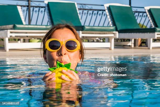 chica con gafas de sol sosteniendo y disfrutando de su bebida en la piscina - mothers day beach fotografías e imágenes de stock