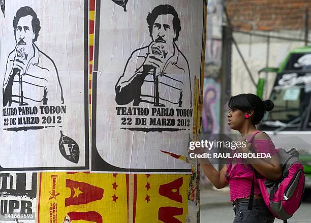 Woman passes by posters with the image of deceased Colombian drug lord Pablo Escobar along a street of Medellin, Antioquia department, Colombia, on...