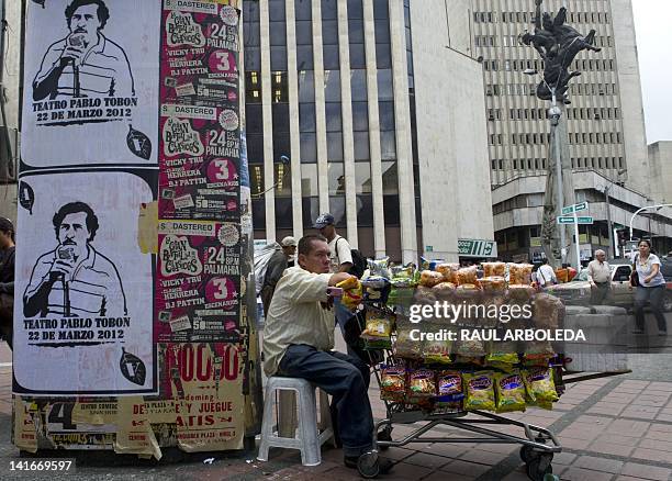 Peddler stays by posters with the image of deceased Colombian drug lord Pablo Escobar along a street of Medellin, Antioquia department, Colombia, on...