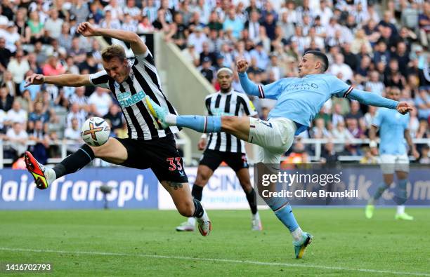 Phil Foden of Manchester City attempts to shoot at goal past Dan Burn of Newcastle United during the Premier League match between Newcastle United...