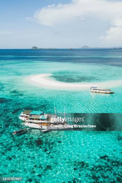 tourist diving boat on coral reef with clear turquoise ocean water and small sandy beach on background - nusa tengara oriental imagens e fotografias de stock