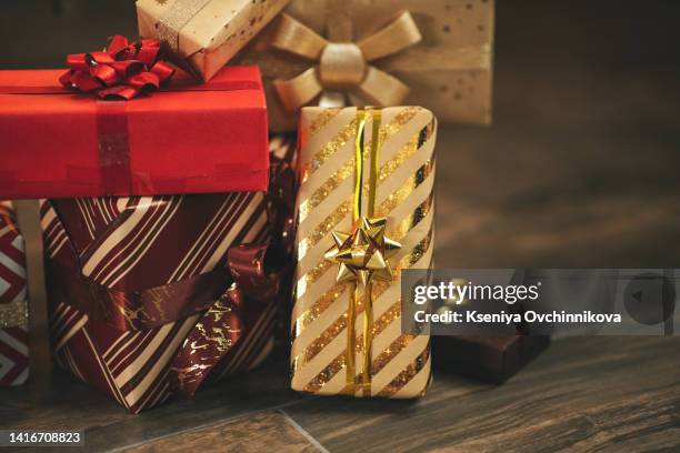 photo of luxury gift boxes under christmas tree, new year home decorations, golden wrapping of santa presents, festive tree decorated with garland, baubles, traditional celebration. copy space - gift under christmas tree stock pictures, royalty-free photos & images