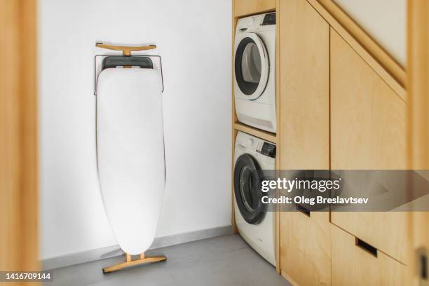 modern cloakroom with built-in washing and drying machines and ironing board. wooden wardrobe. minimalist scandinavian style - bügelbrett stock-fotos und bilder