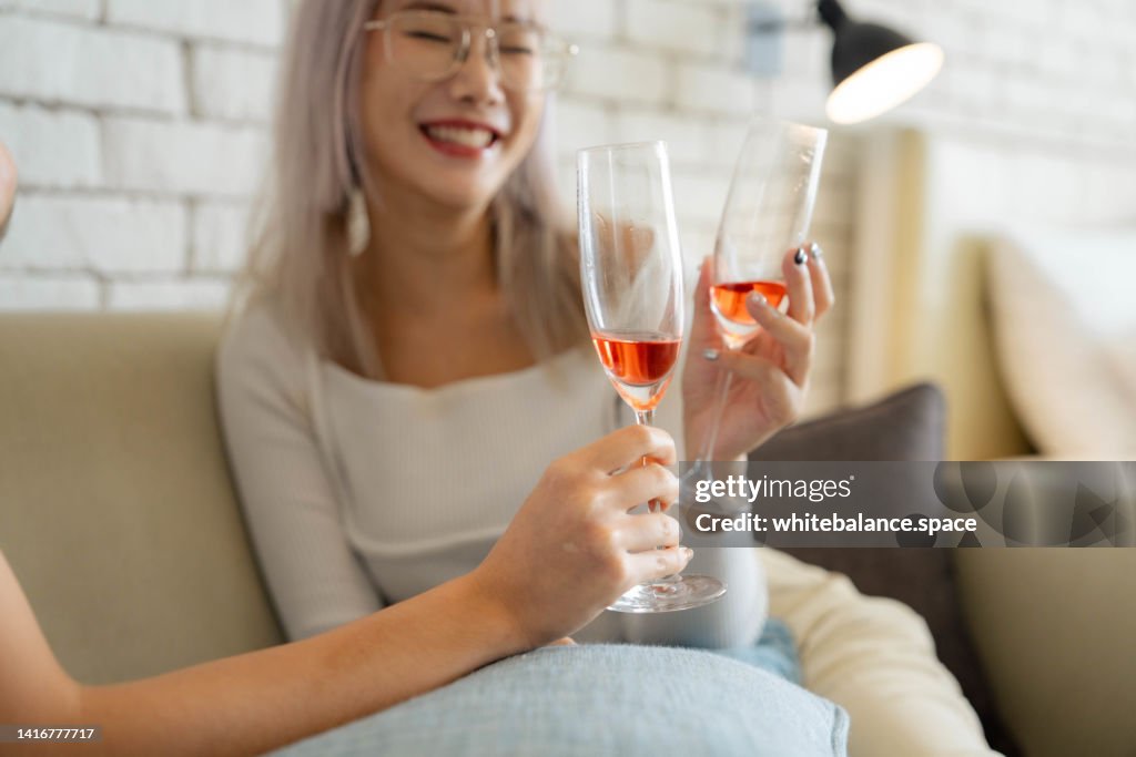 Cheerful Asian lesbian couple celebrating anniversary.