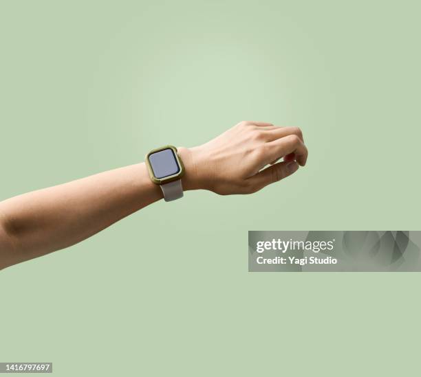 woman using a smart watch against green background - watch timepiece photos et images de collection