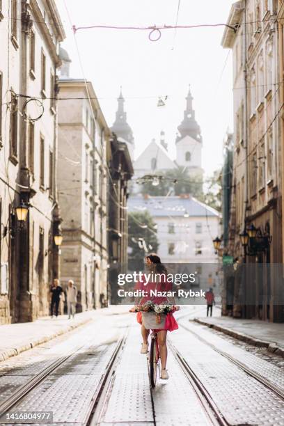 the beautiful woman peddling through the city at the sunrise - summer of 77 stock pictures, royalty-free photos & images