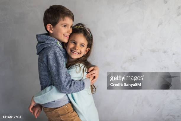 lächelnde, liebevolle kleine kinder umarmen sich - nur kinder stock-fotos und bilder