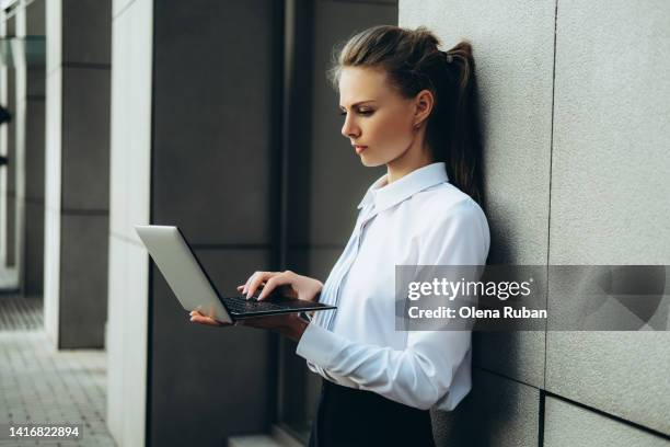 young woman working on laptop outdoors. - grey blouse stock pictures, royalty-free photos & images