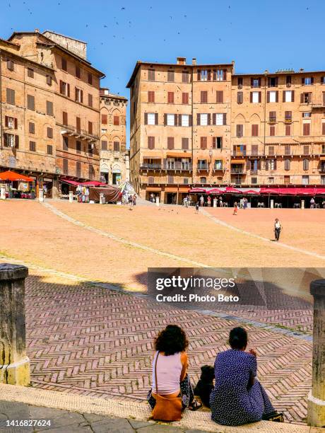 a couple of girls admire piazza del campo in the heart of the medieval town of siena in tuscany - praça do campo imagens e fotografias de stock