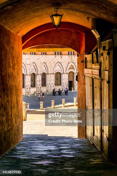 a suggestive arched alley leads to piazza del campo in the medieval heart of siena in tuscany - praça do campo imagens e fotografias de stock