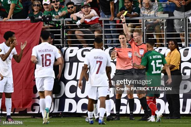 Canadian referee Drew Fischer shows a yellow card to Qatar's midfielder Assim Madibo after arguing with US 1st Assistant referee Kathryn Nesbitt...