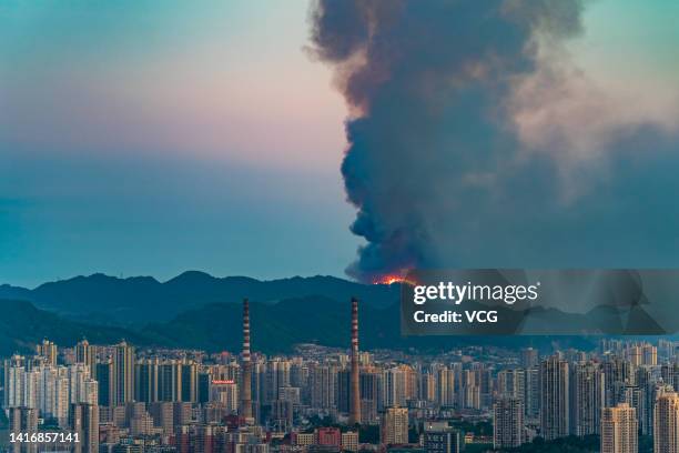 Smoke and flames rise into the sky during a mountain forest fire triggered by persistent drought and heat waves on August 21, 2022 in Chongqing,...