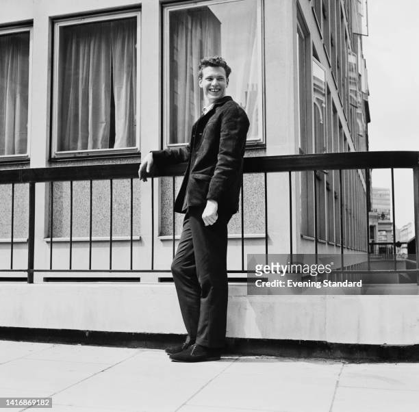 British record producer and songwriter Charles Blackwell smiling as he poses beside a guardrail outside EMI House in Manchester Square, London,...