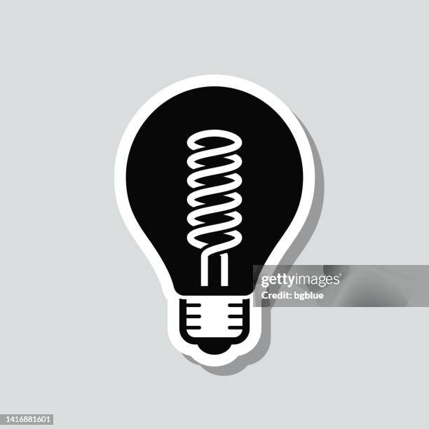 glühbirne mit spiralfaden. symbolaufkleber auf grauem hintergrund - energy efficient lightbulb stock-grafiken, -clipart, -cartoons und -symbole