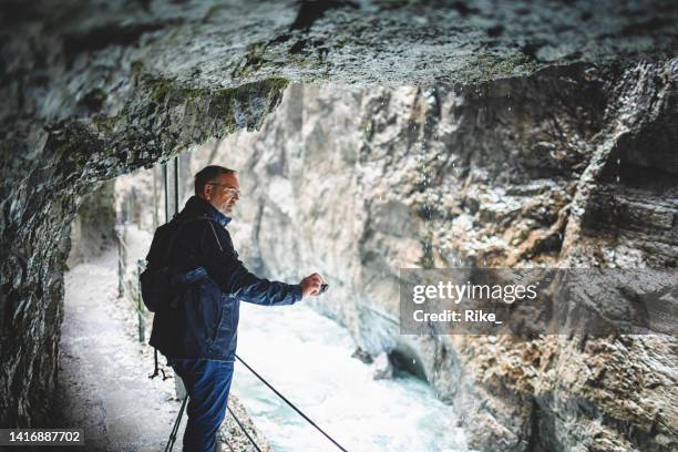 attractive man sightseeing gorge and taking photos in bavaria - partnach gorge stock pictures, royalty-free photos & images