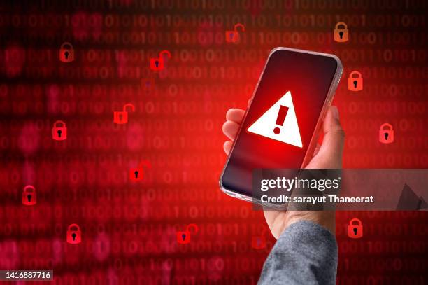 hacker in hoodie dark theme hacker in a blue hoody standing in front of a coding background with binary streams and information security terms cybersecurity concept - danger sign stock-fotos und bilder