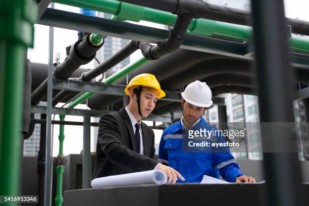 engineer is working on the roof of building. surrounding with high building. - site visit stock pictures, royalty-free photos & images