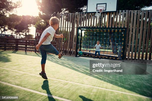 two little boys playing soccer in the schoolyard - urban football pitch stock pictures, royalty-free photos & images